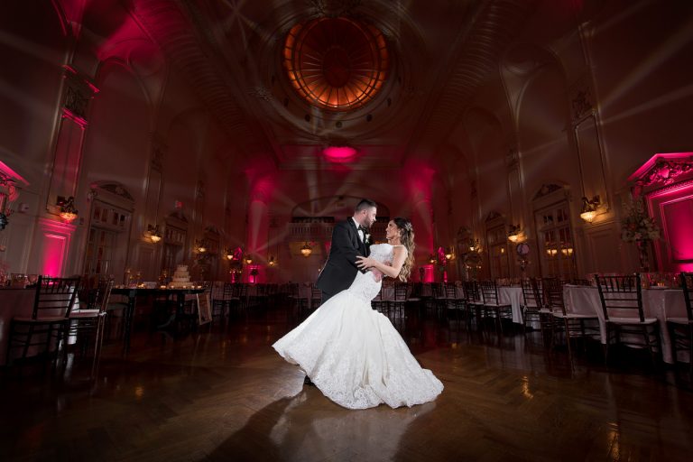 Bride and groom dancing together in a beautifully lit wedding reception venue.