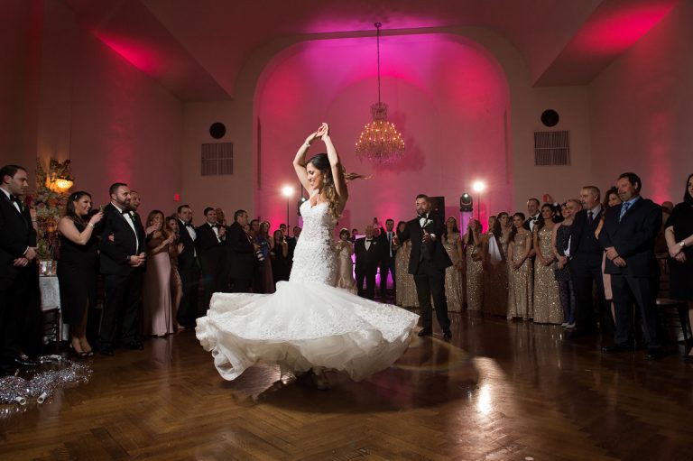 Bride in a white wedding dress dancing with a groom during their first dance at a wedding reception.