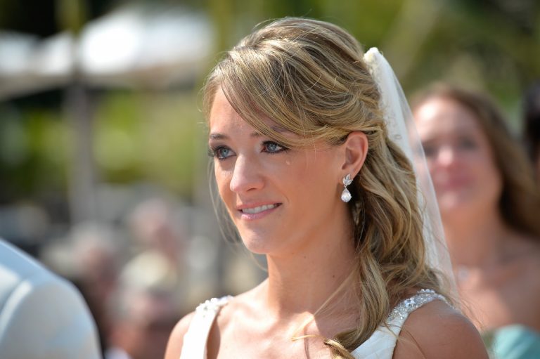 Bride with a tear on her cheek during a wedding ceremony, wearing a white dress and veil.