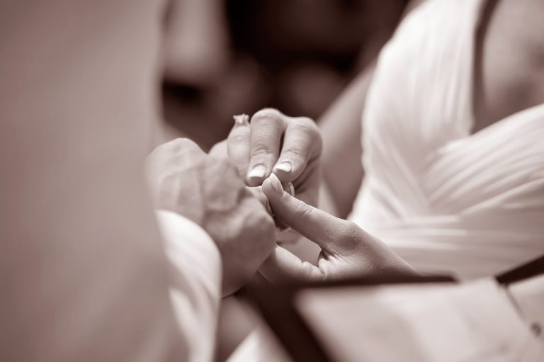 A close-up of hands exchanging wedding rings during a ceremony.
