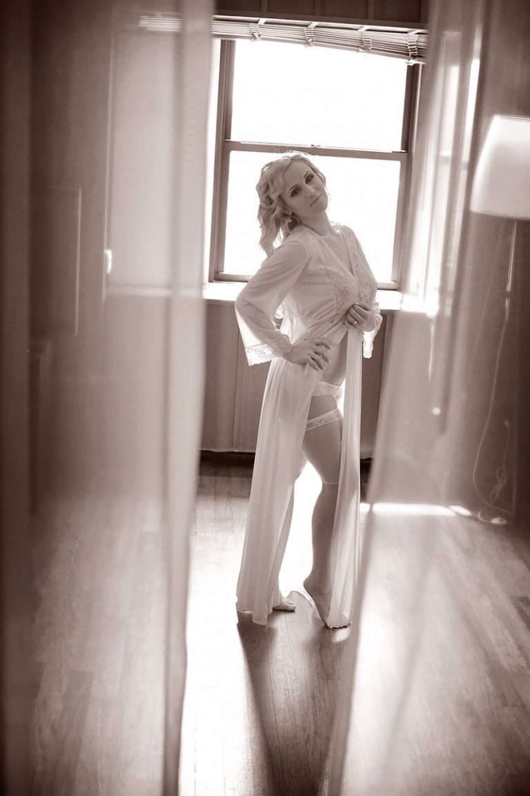 Bride posing in a boudoir outfit with a soft focus effect in a well-lit room.