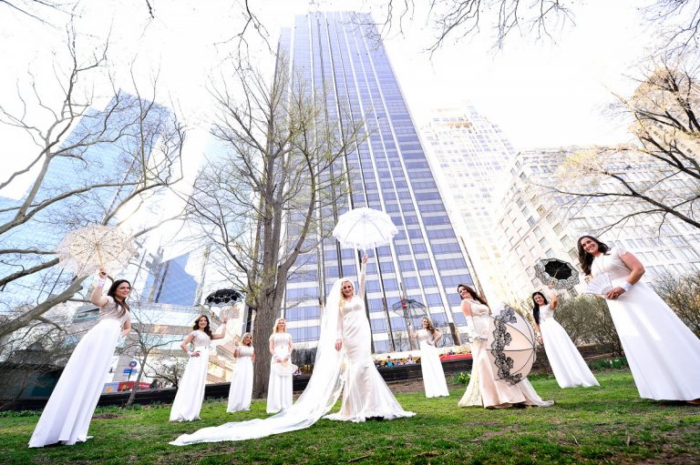 Bridal party wearing white dresses holding umbrellas in Central Park, New York City.