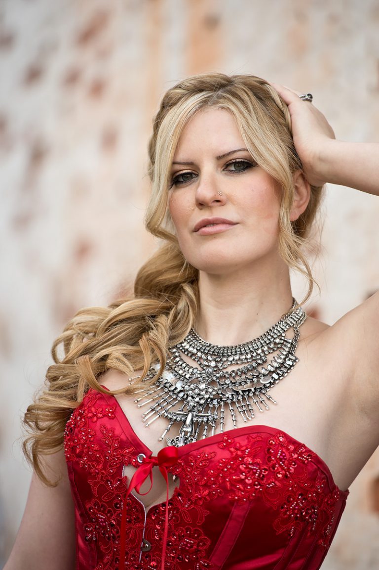 A bride wearing a red dress adorned with intricate beading and a large statement necklace.