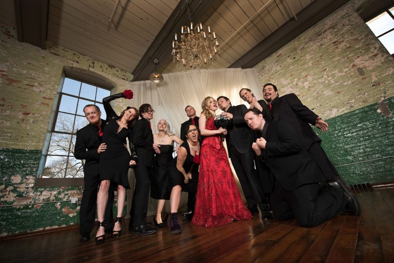 Bridal party dressed in Gothic Victorian attire posing together in a rustic indoor setting.
